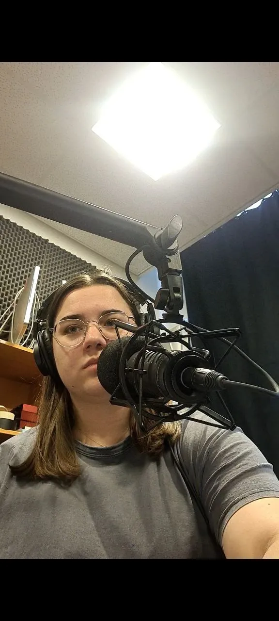 Estelle en train d’enregistrer l’épisode pilote dans un studio de podcast, casque sur les oreilles devant un micro