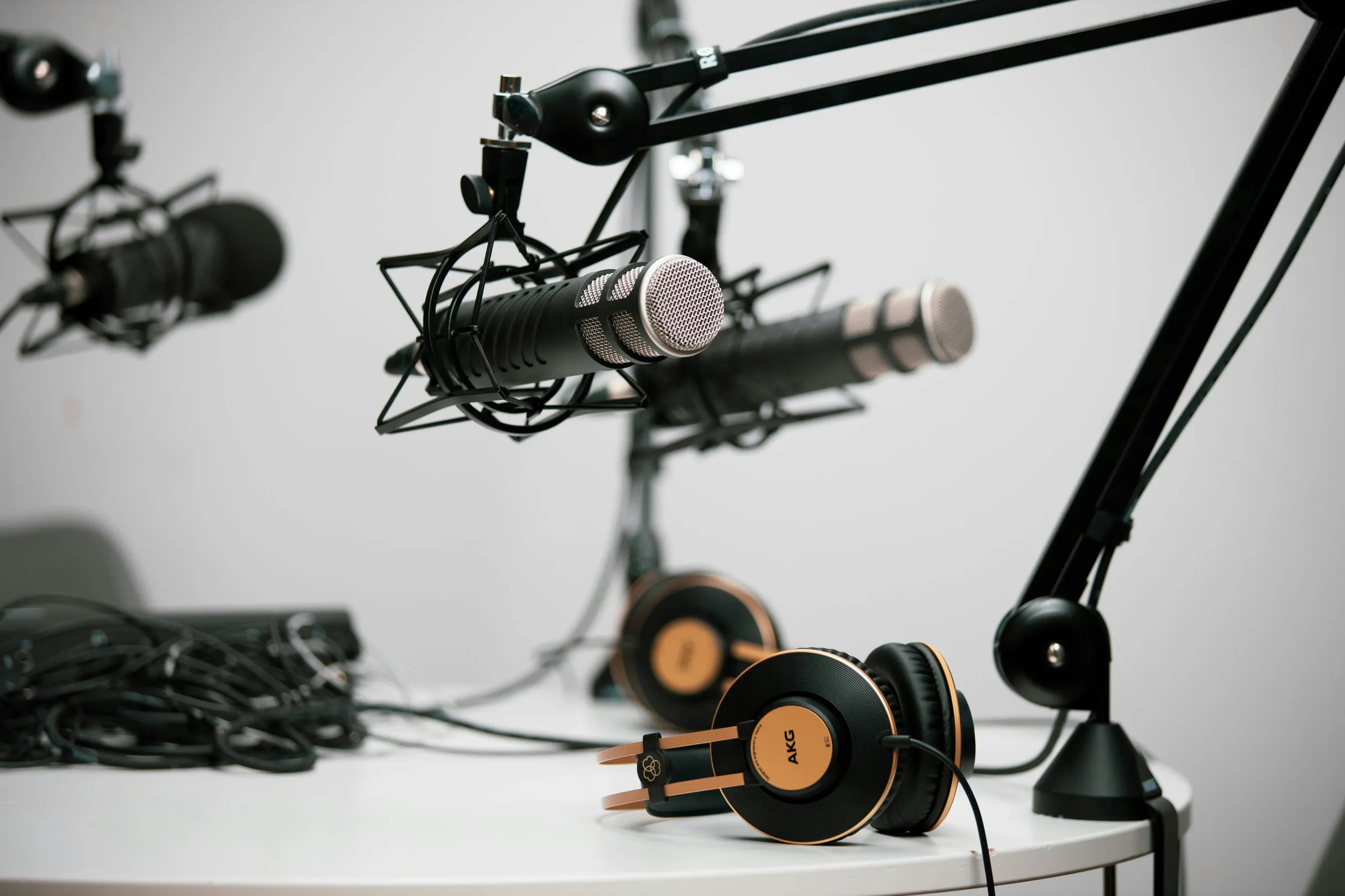Micros de studio sur bras articulés et casques posés sur une table, dans une salle d’enregistrement de podcast