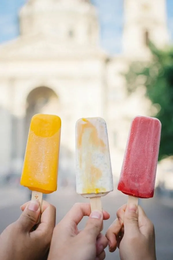 Trois glaces à l’eau colorées tenues à la main